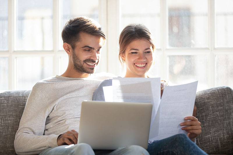 Couple reviewing loan docs on the couch, Mortgage Broker, Mortgage Lender, Mortgage Rates, First Time Home Buyer